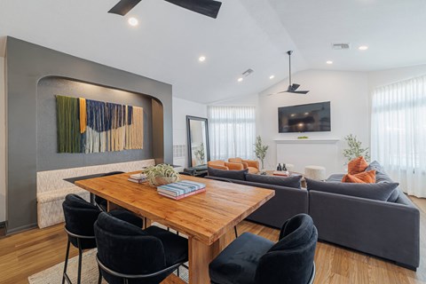 A modern living room with a wooden dining table and grey sofa.