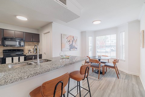 A kitchen with a granite countertop and a dining table with chairs.