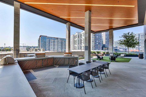 A modern outdoor dining area with a long table and chairs.