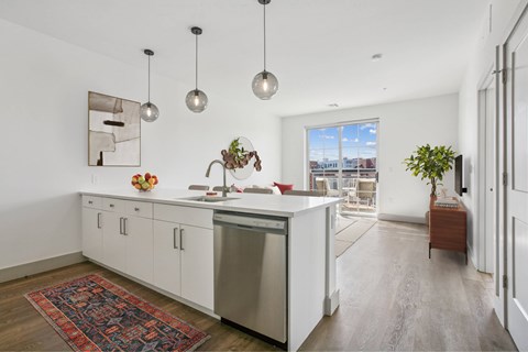 A kitchen with white cabinets and a large window.