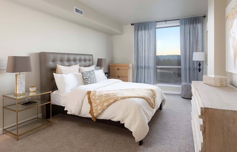 A bedroom with a large bed and a window overlooking a sunset.