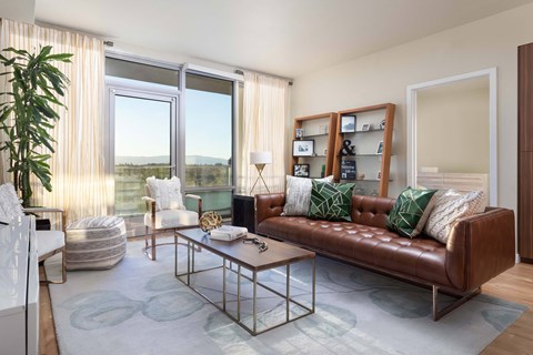 A living room with a brown leather couch and a glass coffee table.