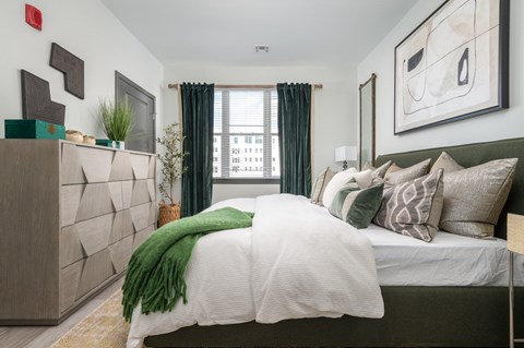A bedroom with a large bed and a green throw blanket.