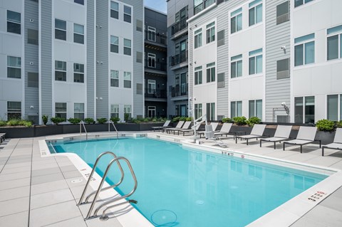 A swimming pool with lounge chairs and a building in the background.