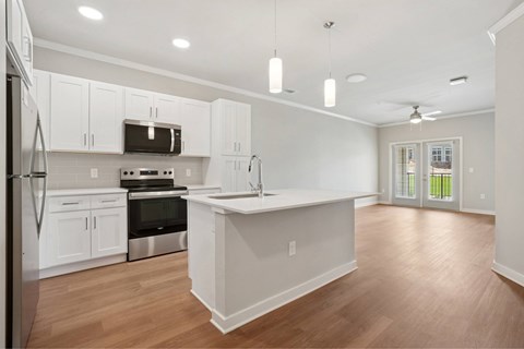 A kitchen with white cabinets and a wooden floor.