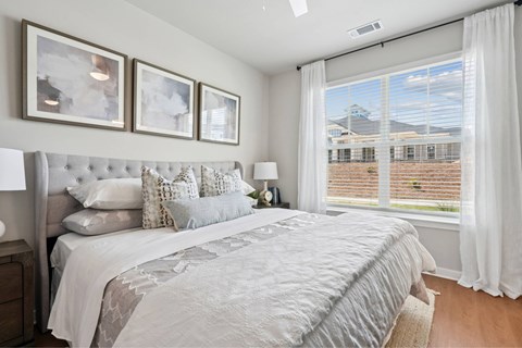 A bedroom with a large bed and a window overlooking a brick building.