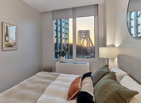 A bedroom with a large bed and a window overlooking a bridge.