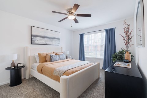 A bedroom with a large bed and a ceiling fan.