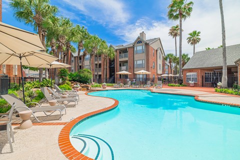 A swimming pool surrounded by lounge chairs and umbrellas.