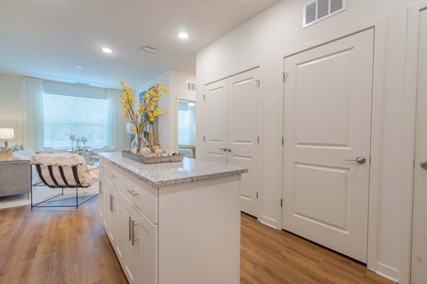 A kitchen with white cabinets and a marble island.