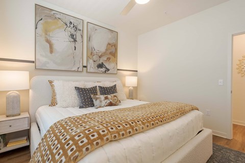 A bedroom with a large bed and two wall art paintings.