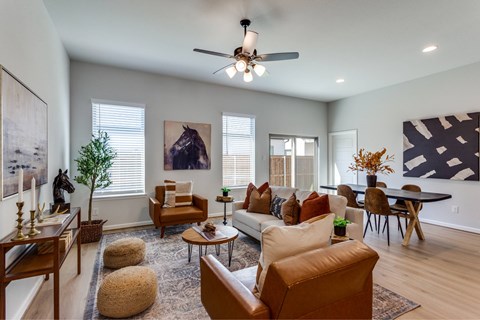 A living room with a brown leather couch and a ceiling fan.