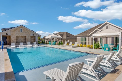 A pool surrounded by lounge chairs and umbrellas.