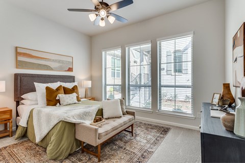 A bedroom with a bed, a bench, and a ceiling fan.