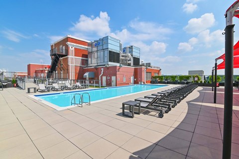 A swimming pool area with lounge chairs and a building in the background.