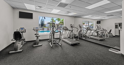 A black and white photo of a gym with a television and exercise equipment.