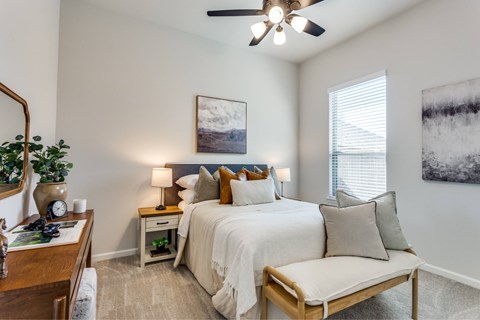 A bedroom with a bed, nightstand, and a ceiling fan.