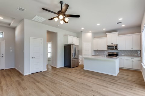 A modern kitchen with a wooden floor and white cabinets.