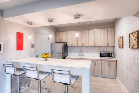 A kitchen with a white counter and bar stools.