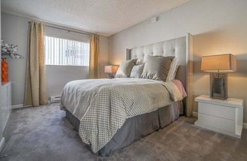 A bedroom with a bed, nightstand, and window.