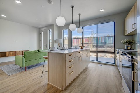 A modern kitchen with a green chair and wooden cabinets.