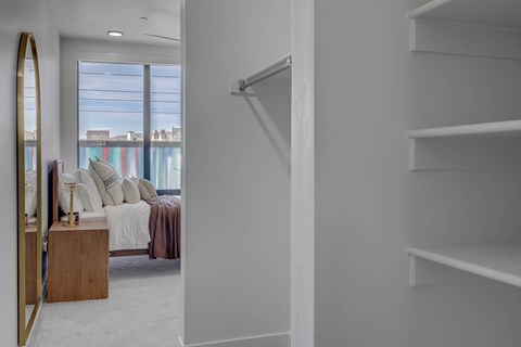 A white bedroom with a bed and a mirror.