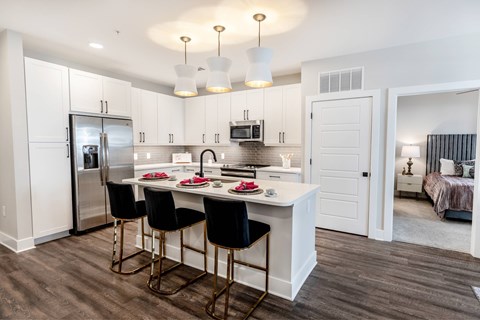 A kitchen with a table and chairs in front of a refrigerator and microwave.
