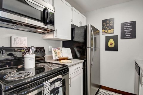 A kitchen with a black stove top and a refrigerator with a magnet on it.