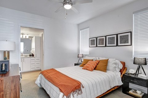 A bedroom with a bed, nightstand, and a ceiling fan.