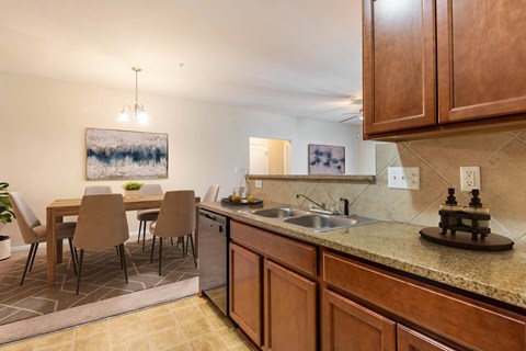 A kitchen with brown cabinets and a painting hanging above the table.