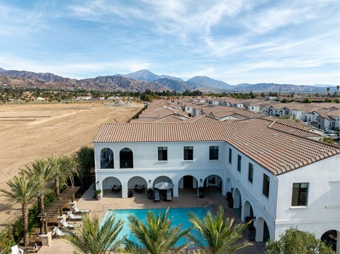 A large white building with a pool and palm trees in front.
