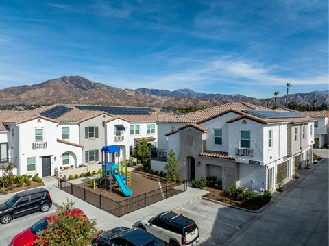 A sunny day at a residential complex with a playground and solar panels on the roofs.