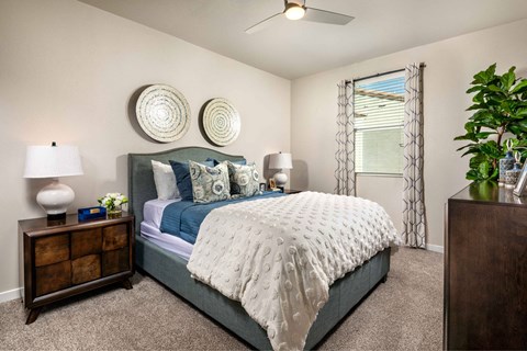 A bedroom with a bed, nightstand, and a plant.