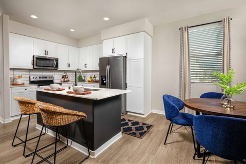 A kitchen with a black island and blue chairs.