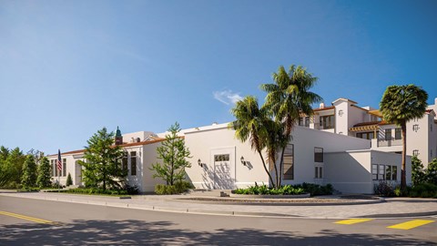 A white building with a flag on it and a tree in front.