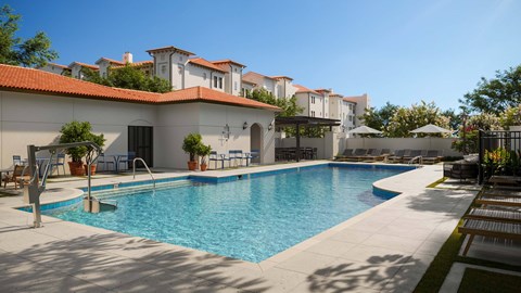 A swimming pool in front of a building with a red tile roof.