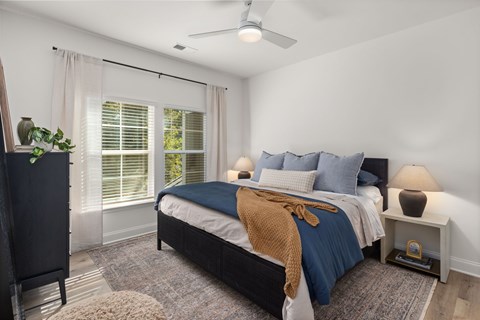 A bedroom with a bed, nightstand, and window with blinds.