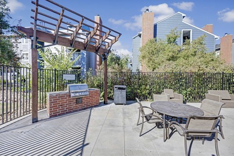 A patio with a table and chairs and a brick fireplace.