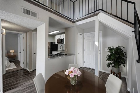 A dining room with a table and chairs and a potted plant.