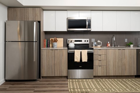 A modern kitchen with a stainless steel refrigerator and wooden cabinets.