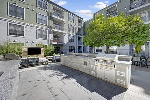 A patio area with a fireplace and seating area in front of apartment buildings.