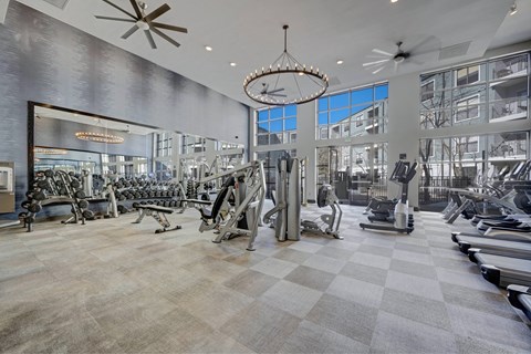 A gym with a variety of equipment including treadmills, weights, and exercise machines.