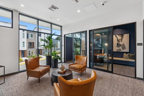 A modern living room with brown chairs and a glass door.