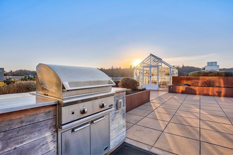 A modern outdoor kitchen with a grill and a table set up on a patio.
