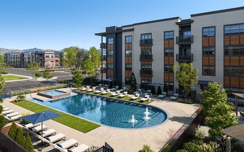 A large swimming pool with a fountain in the middle of a resort style outdoor area.