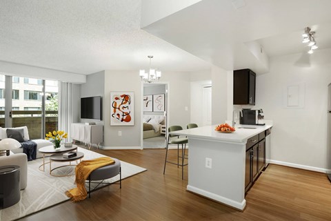 A modern living room with a grey sofa and a white kitchen island.