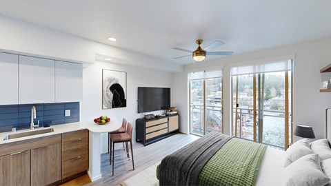 A modern bedroom with a large bed and a kitchen area.