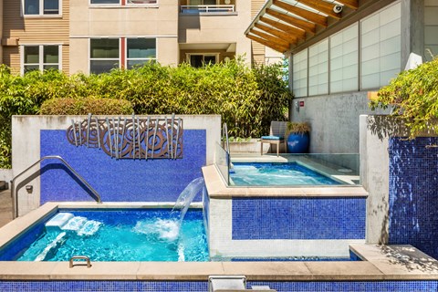 A pool with a blue tiled wall and a metal railing.