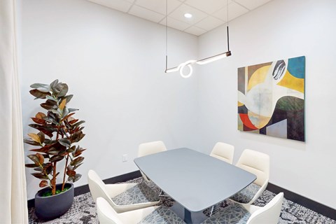 A modern dining room with a grey table and white chairs.