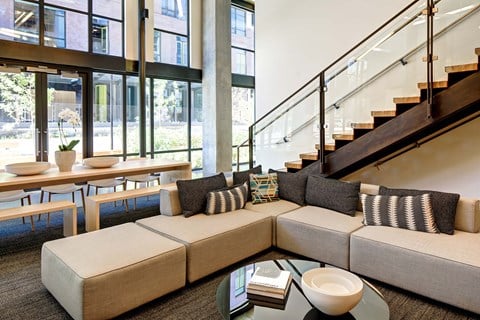 A modern living room with a glass coffee table and a staircase.